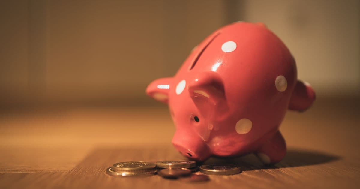Red polka-dot piggy bank surrounded by loose coins on a wooden table