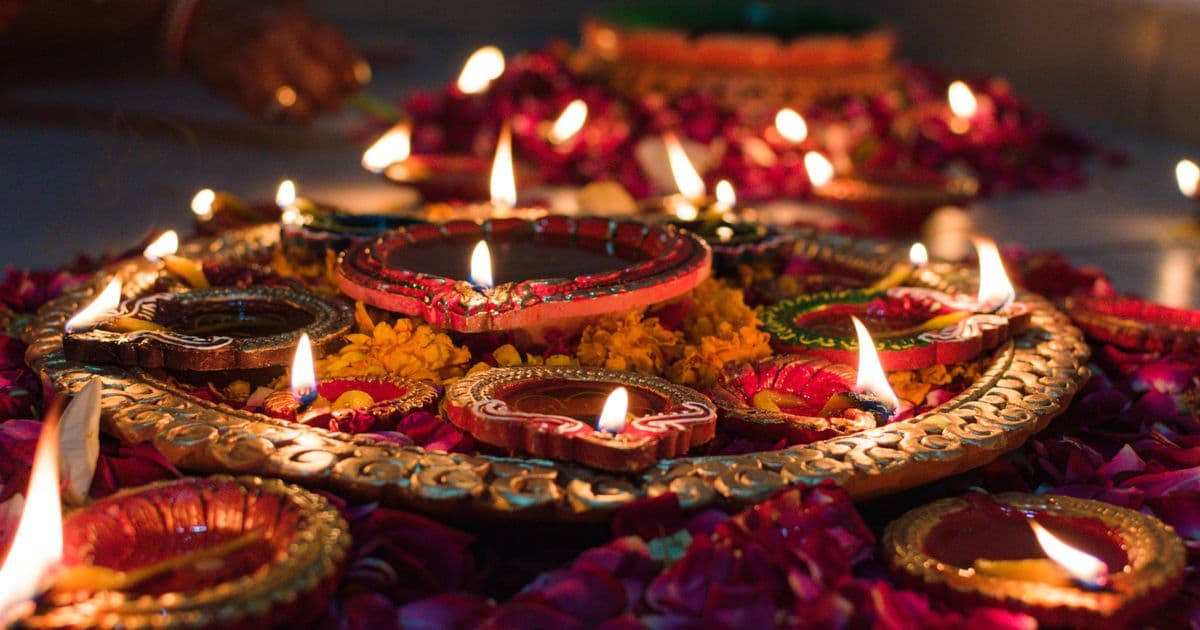 Lit clay diya oil lamps arranged in a row with marigold flowers for Diwali