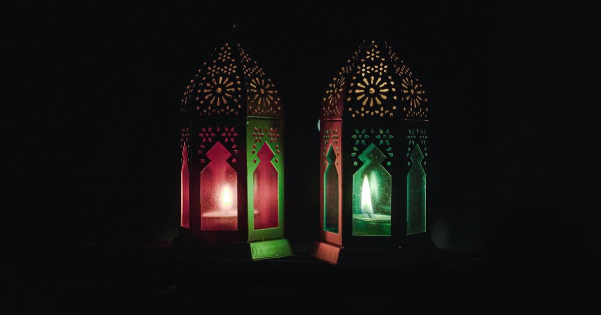 Ornate colorful lanterns lit with candles glowing against a dark background