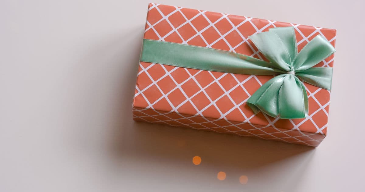 Gift box in coral diamond-pattern wrapping paper with a mint green ribbon bow