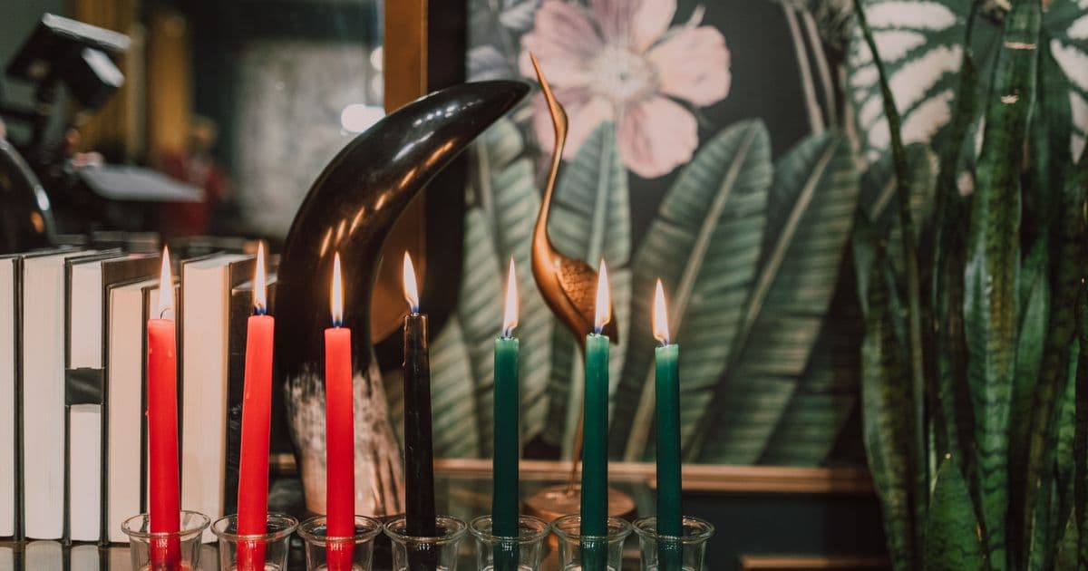 Red, black, and green candles lit in a row, representing Kwanzaa's seven principles
