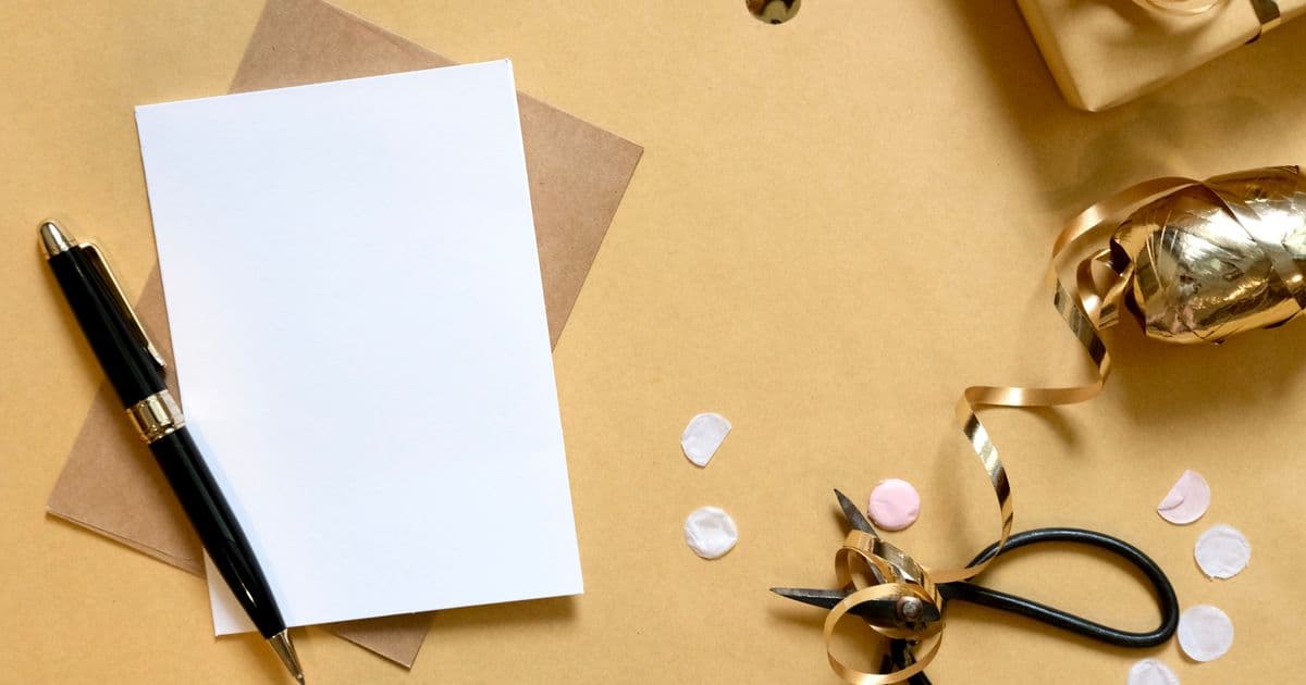 Overhead flat lay of a blank card, pen, scissors and gift-wrapping supplies