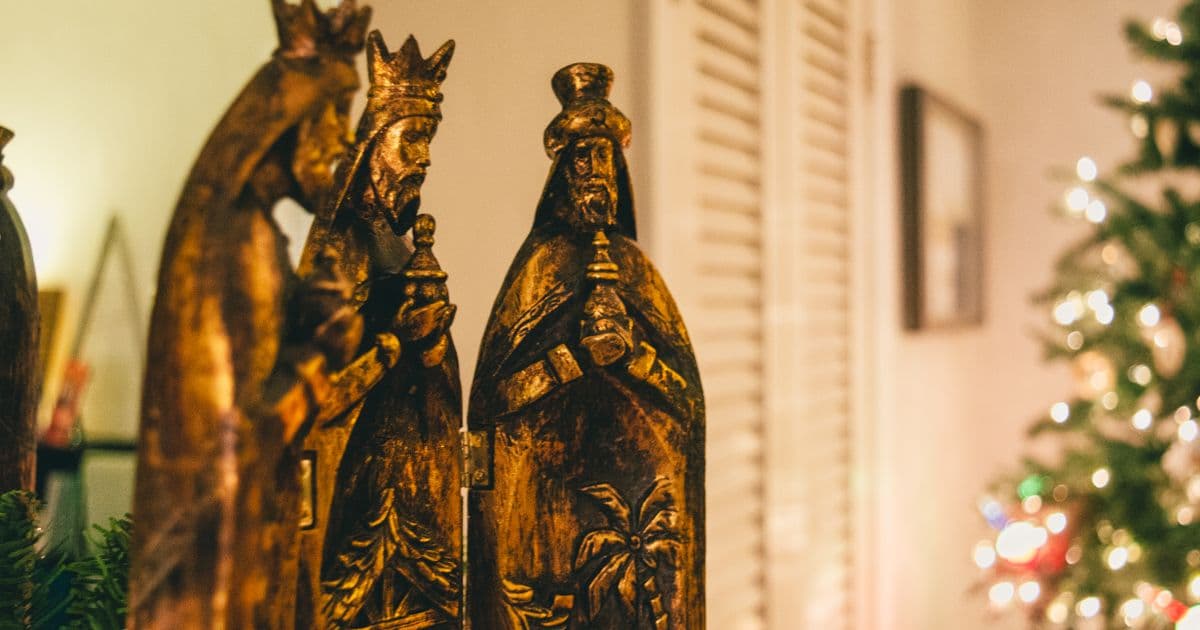 Wise Men figurines beside a lit Christmas tree, representing Three Kings Day